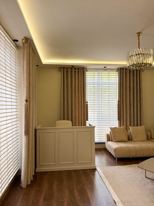 Bekleme odasında geniş pencere, perdeler ve oturma alanı